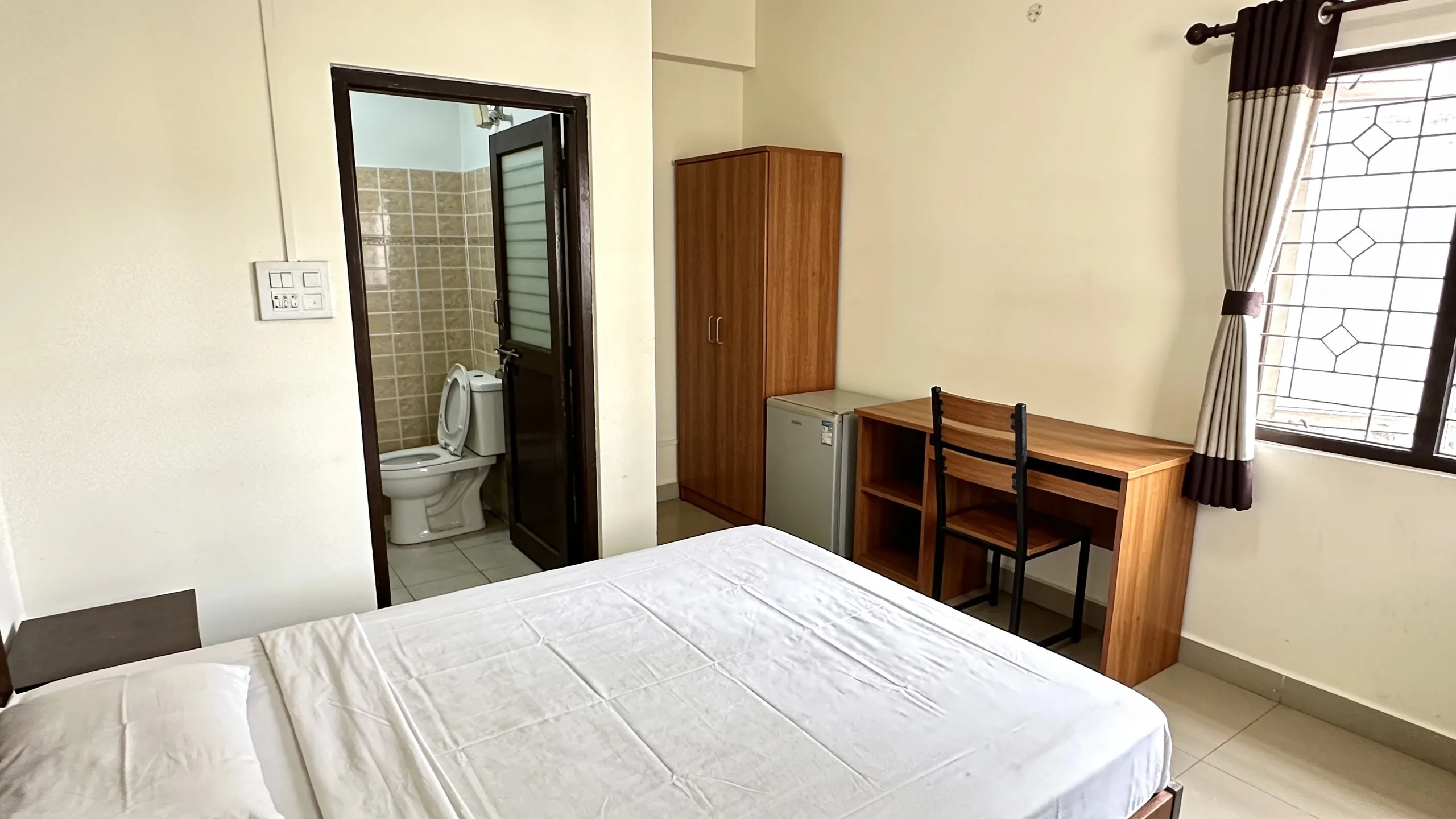 PG room in Indian city with attached bathroom and study desk